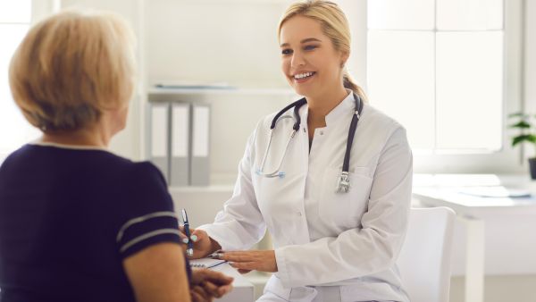 Médica recebendo idosa para fazer exames de rastreamento de câncer colorretal