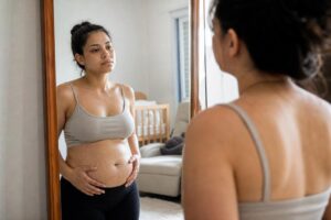 Imagem ilustrativa gerada por IA mostra mulher observando mudanças do corpo pós-parto durante o período de recuperação após a gravidez.