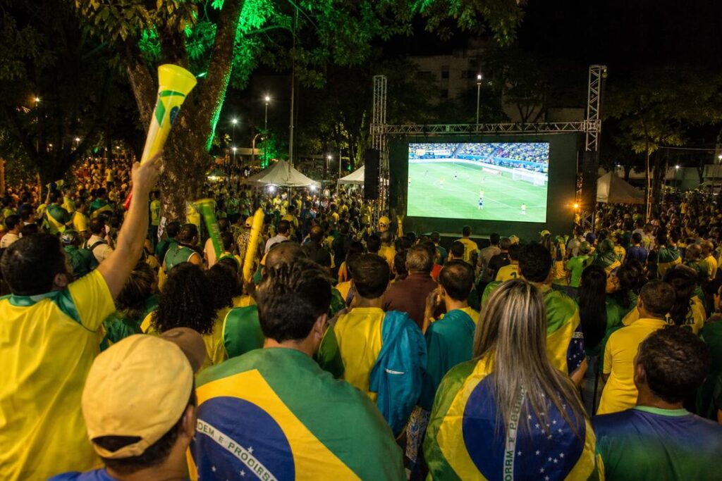 Imagem ilustrativa gerada por IA representando um telão instalado em praça pública para transmissão do Brasil x Escócia em Timóteo.