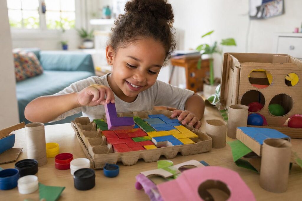 Imagem ilustrativa de criança realizando brincadeiras sem telas com materiais recicláveis para estimular o desenvolvimento infantil.
