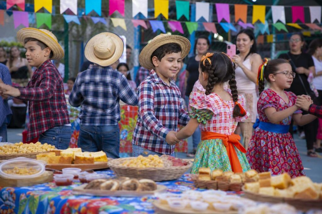 Imagem ilustrativa gerada por IA de crianças participando de festas juninas inclusivas em ambiente adaptado para pessoas autistas.