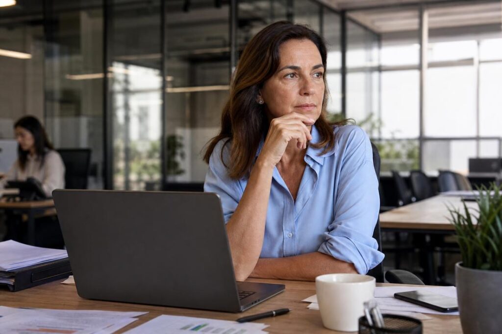 Mulher em ambiente corporativo refletindo sobre os impactos da menopausa no mercado de trabalho