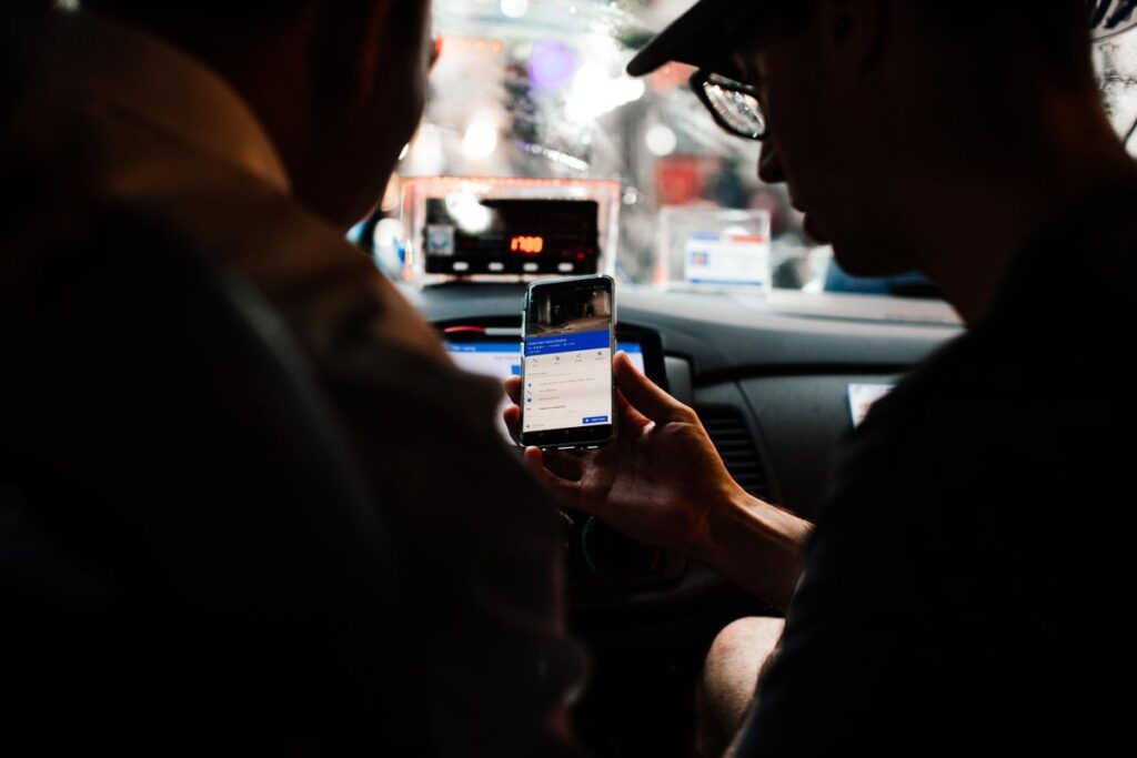 Passageiro com o celular em um carro de aplicativo, tema dos direitos da pessoa autista no transporte. Foto: Pexels