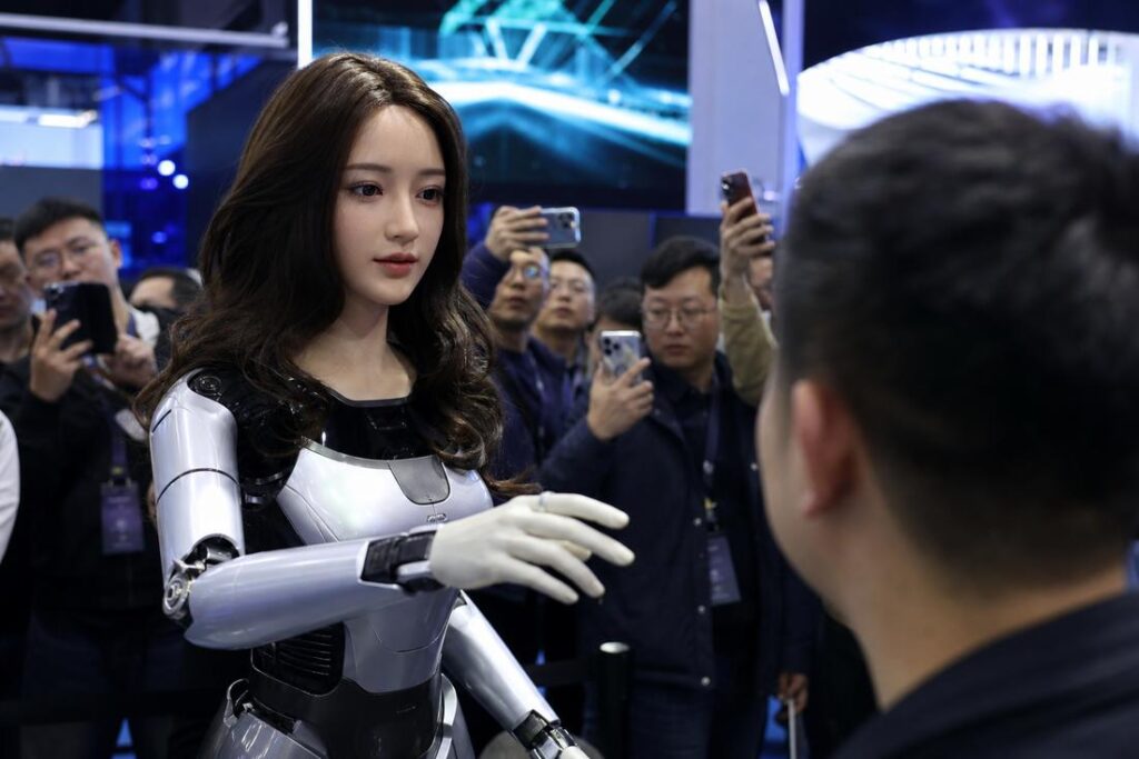 Robô humanoide feminino ultrarrealista, com rosto de aparência humana e corpo robótico branco, interage com um homem em uma feira de tecnologia
