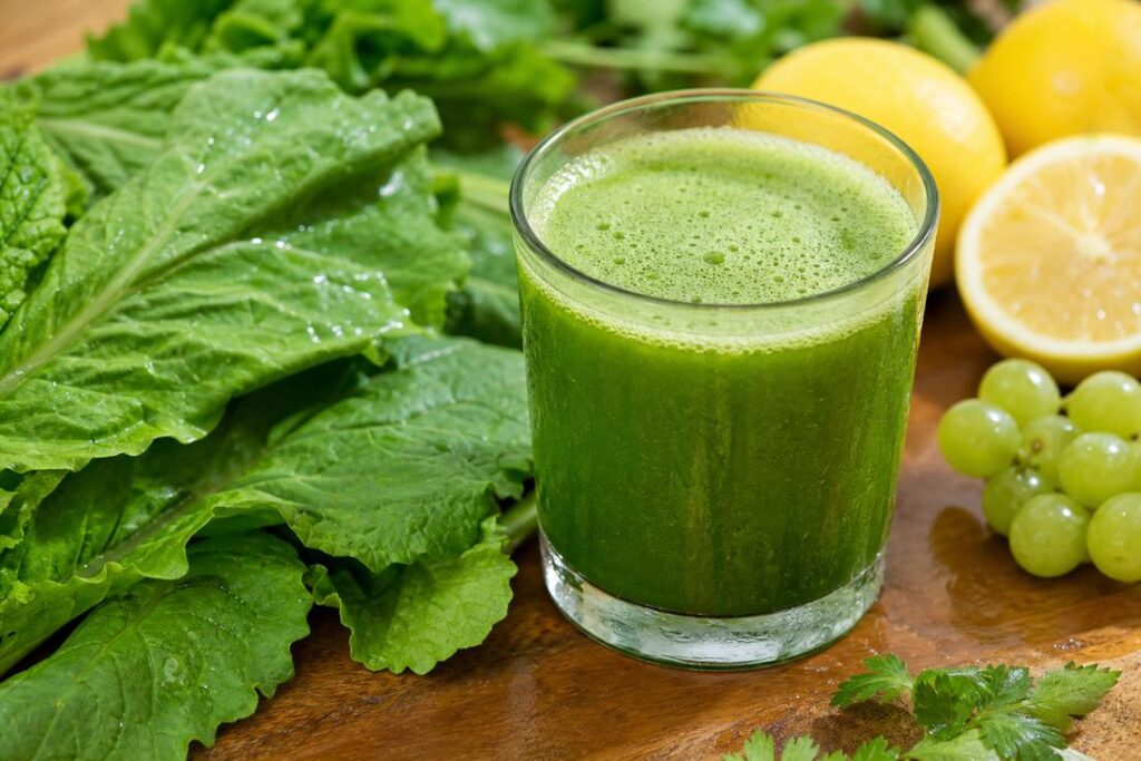 Suco verde de mostarda e limão servido em copo com folhas e frutas frescas