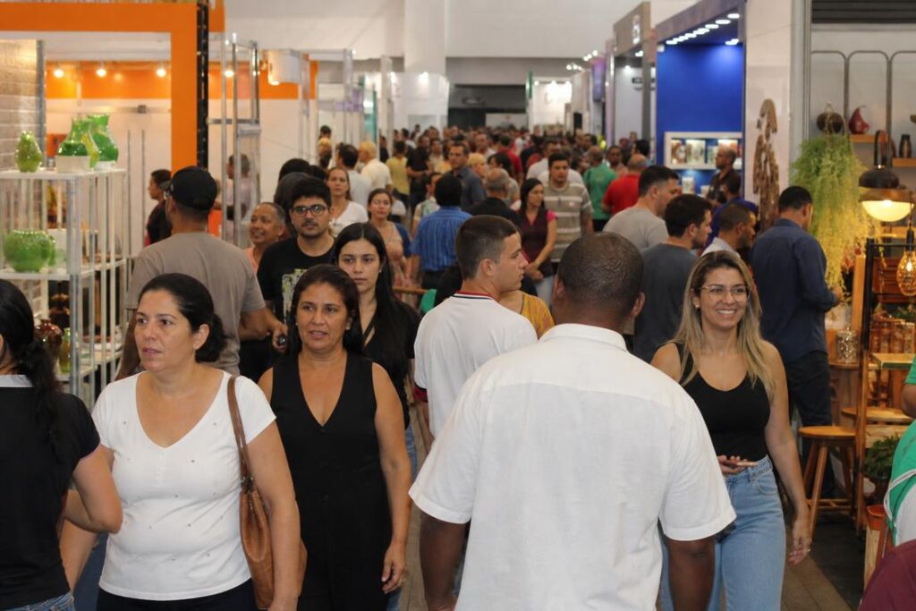 Corredor lotado de visitantes entre estandes iluminados durante a Expo Usipa, em Ipatinga